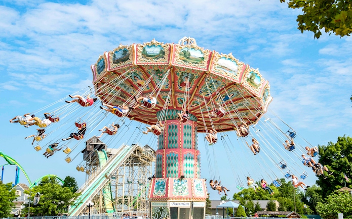 Wave Swinger ride at Dorney Park with people enjoying the swings against a clear sky.