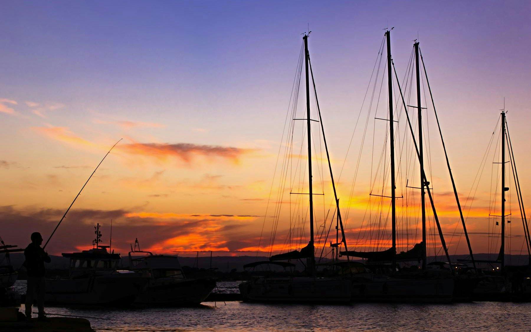 Sailboats at sunset in Ortigia harbor during a sunset tour with aperitif.