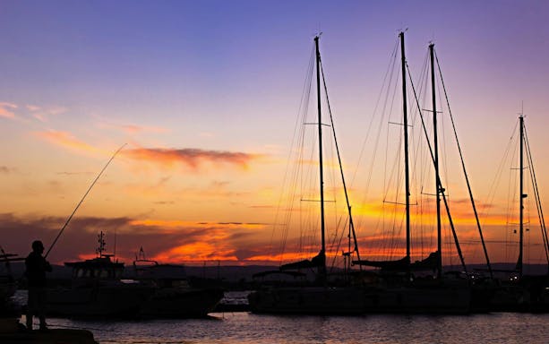 Sailboats at sunset in Ortigia harbor during a sunset tour with aperitif.