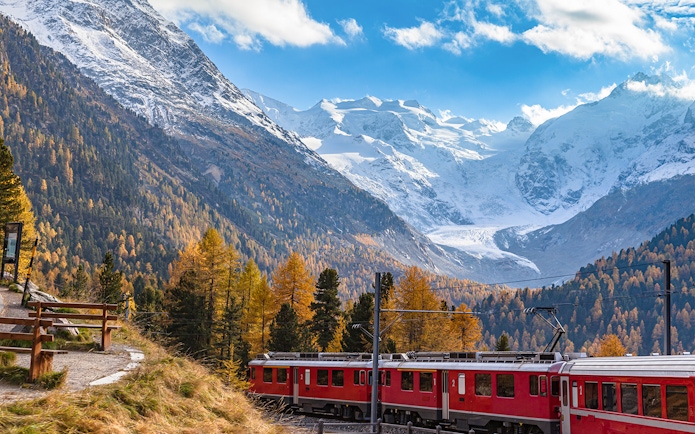 Bernina Express train near Morteratsch Glacier with snow-capped mountains in the background.