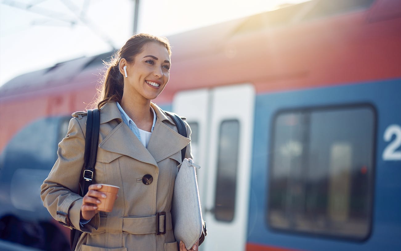 Young woman with coffee at a train station platform.