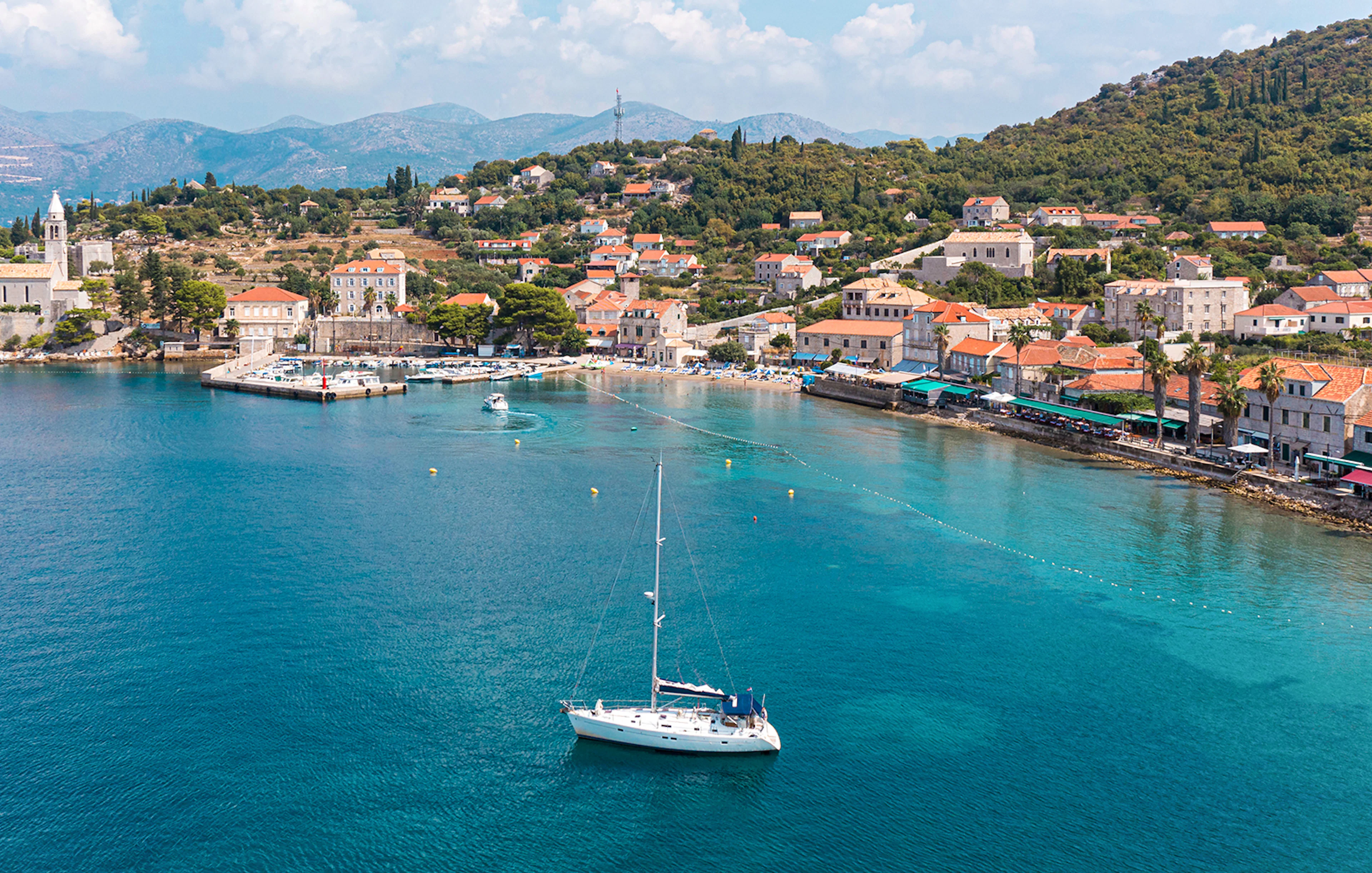 Sailboat near Dubrovnik coast with view of Elaphiti Islands and historic buildings.