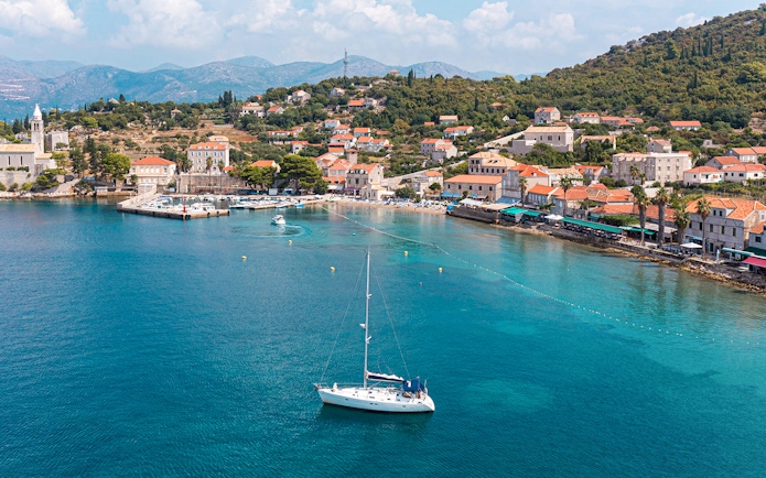 Sailboat near Dubrovnik coast with view of Elaphiti Islands and historic buildings.