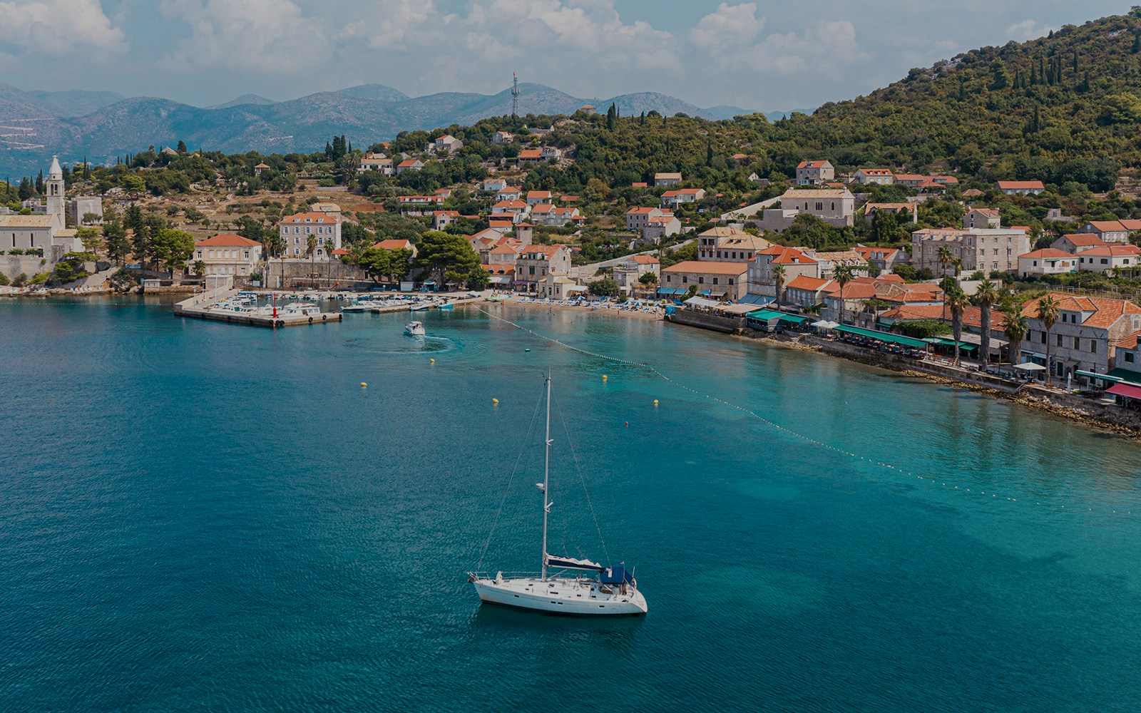 Sailboat near Dubrovnik coast with view of Elaphiti Islands and historic buildings.