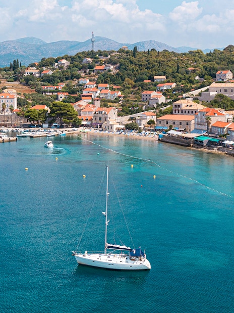 Sailboat near Dubrovnik coast with view of Elaphiti Islands and historic buildings.