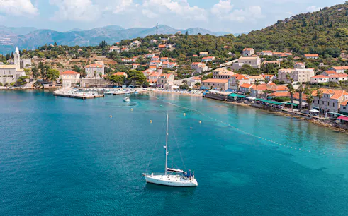 Sailboat near Dubrovnik coast with view of Elaphiti Islands and historic buildings.