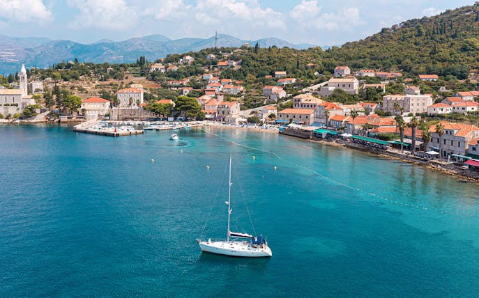 Sailboat near Dubrovnik coast with view of Elaphiti Islands and historic buildings.