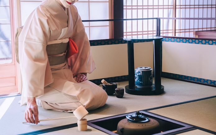 Traditional Japanese tea ceremony with a person in kimono preparing tea in a tatami room.