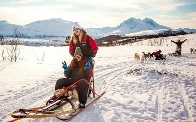 Guests enjoying husky sledding tour in snowy Tromso landscape.
