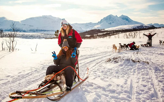 Guests enjoying husky sledding tour in snowy Tromso landscape.