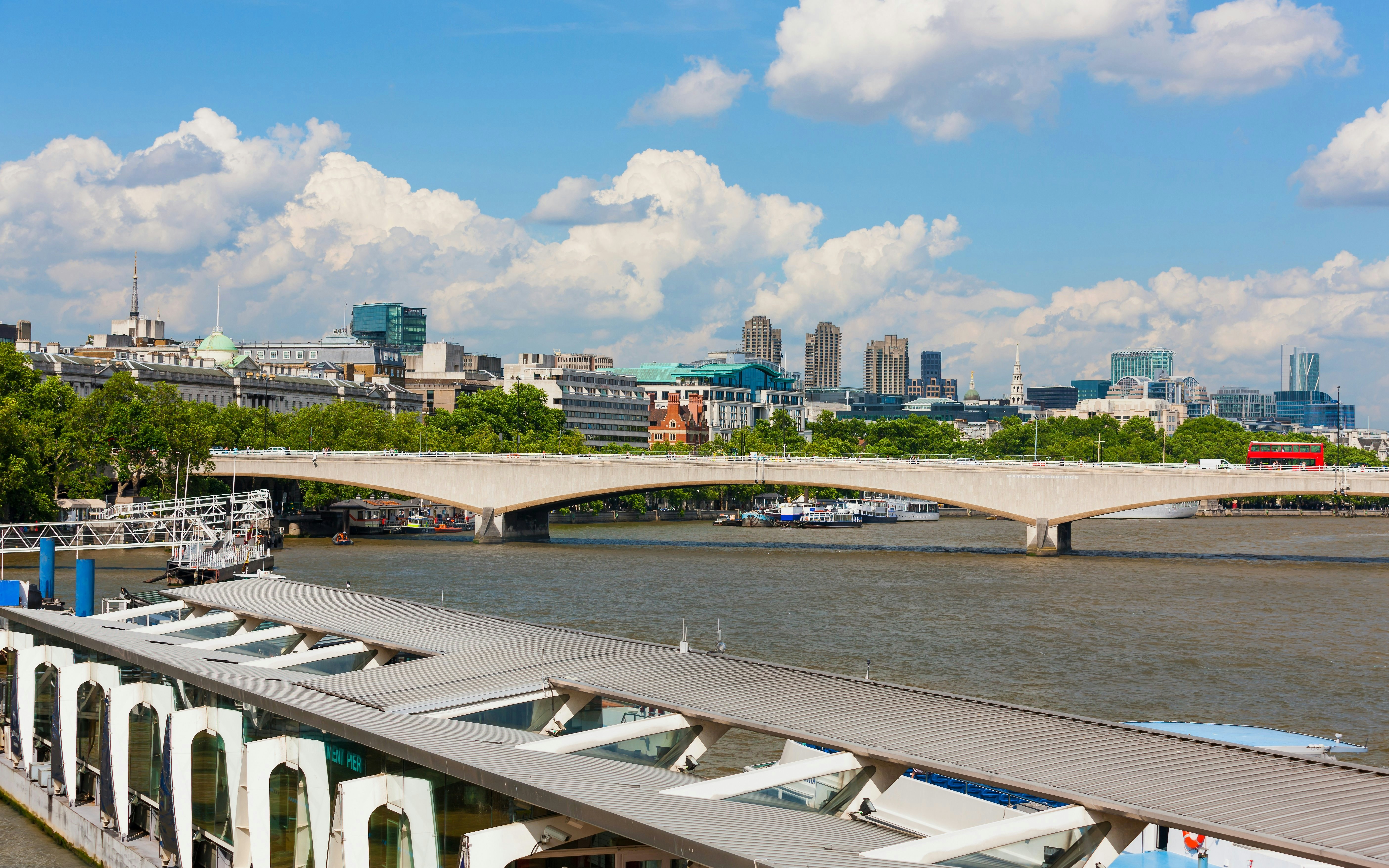 Riverside view of Waterloo Bridge over River Thames, London, with Embankment Pier in foreground.