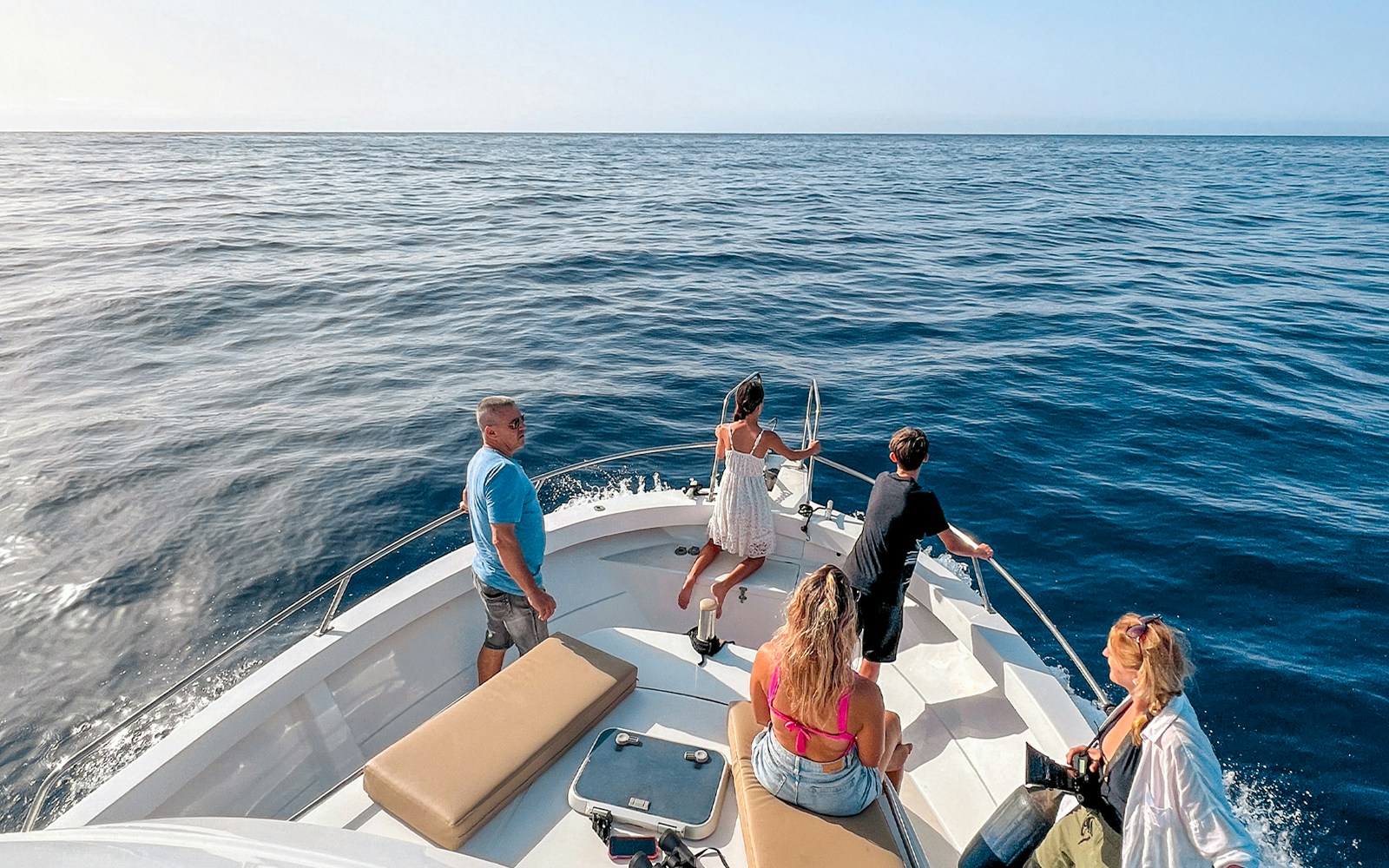 Tourists on a boat enjoying the ocean view during a dolphin and whale watching cruise in Gran Canaria.