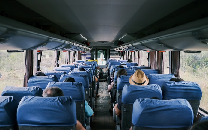 Passengers seated inside a tour bus traveling from Paris to Mont St. Michel's Abbey.