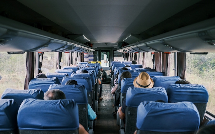 Passengers seated inside a tour bus traveling from Paris to Mont St. Michel's Abbey.