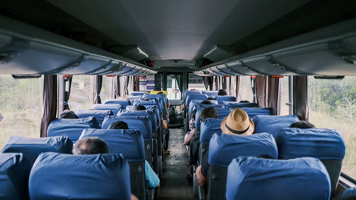 Passengers seated inside a tour bus traveling from Paris to Mont St. Michel's Abbey.