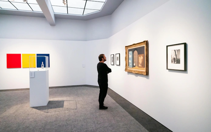 Visitor viewing art at Groeningemuseum, Bruges, featuring modern and classic paintings.