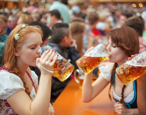Friends celebrating Oktoberfest with beer mugs in a lively festival setting, Germany.