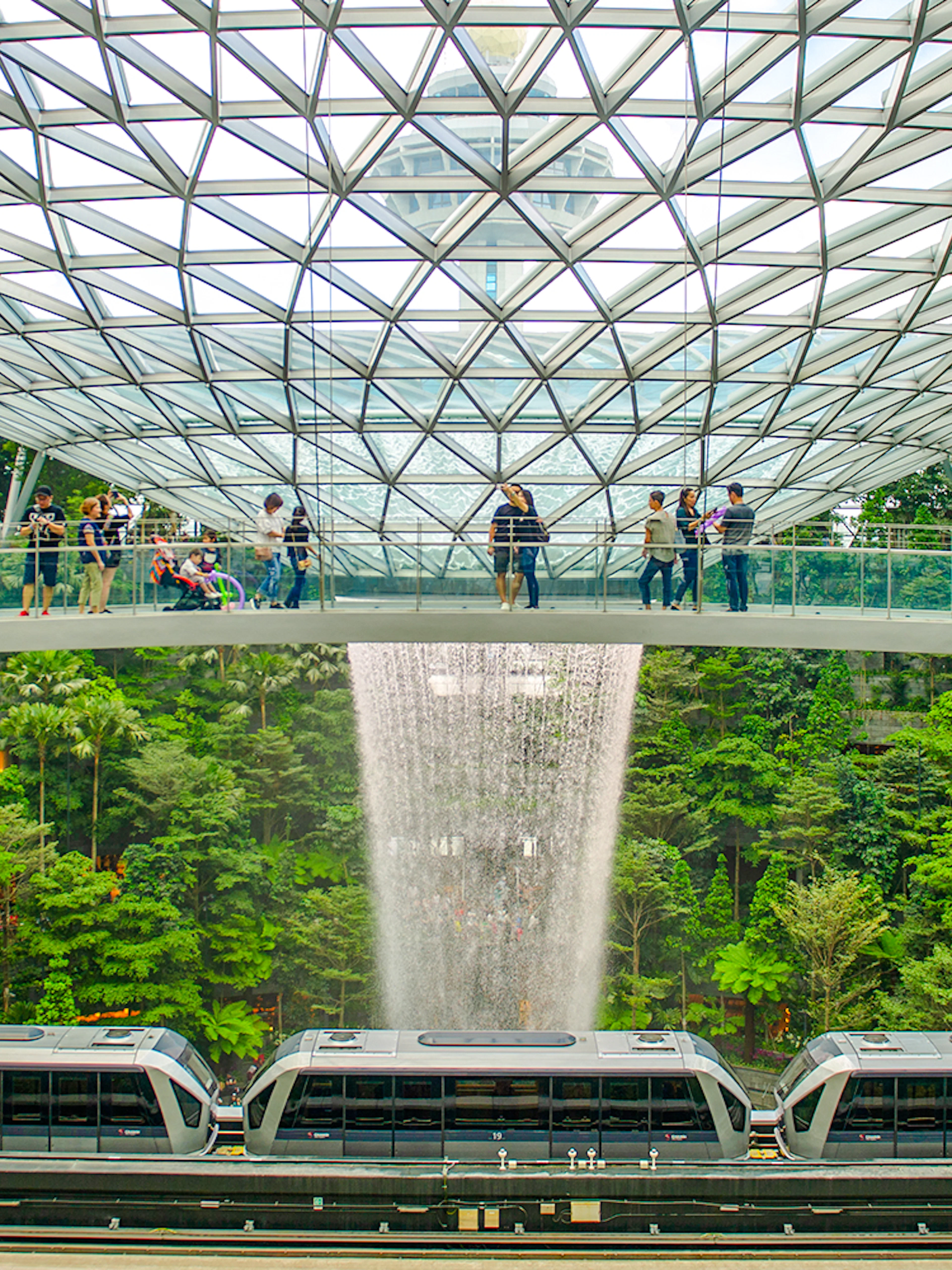 Canopy Bridge at Jewel Changi with waterfall and train below.