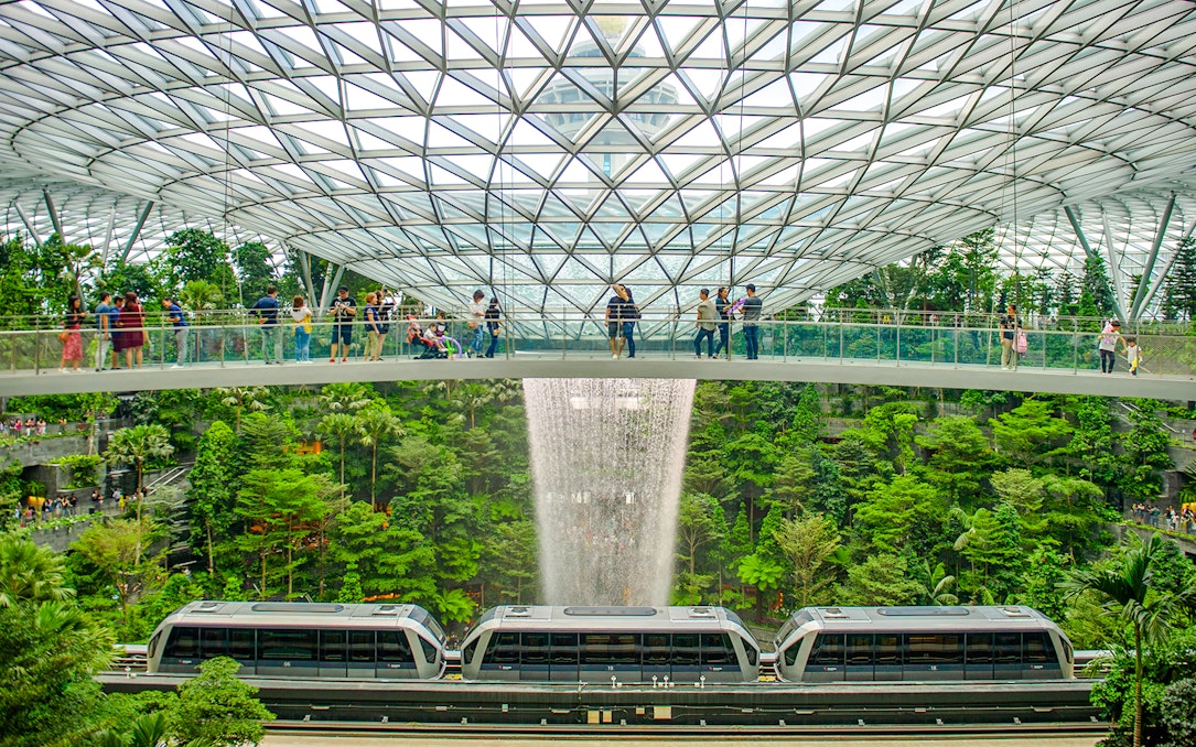 Canopy Bridge at Jewel Changi with waterfall and train below.