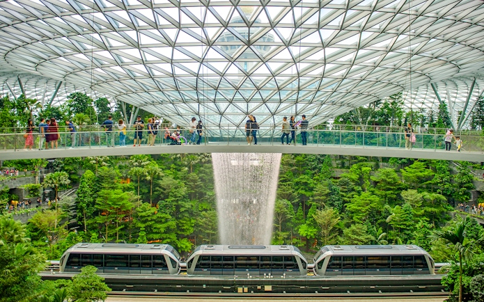 Canopy Bridge at Jewel Changi with waterfall and train below.