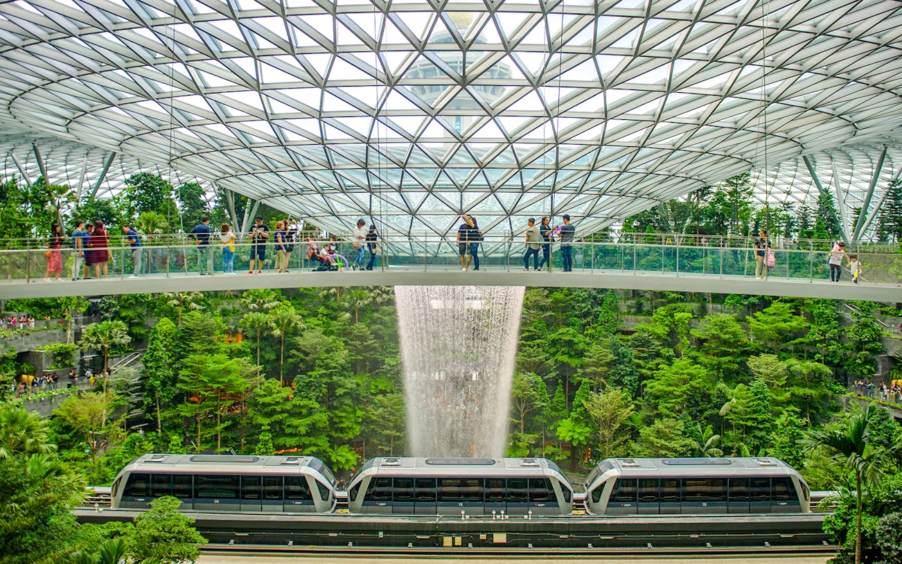 Canopy Bridge at Jewel Changi with waterfall and train below.