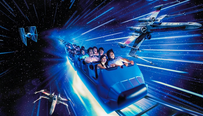 Roller coaster riders on Hyperspace Mountain, Hong Kong Disneyland, surrounded by Star Wars spacecraft.