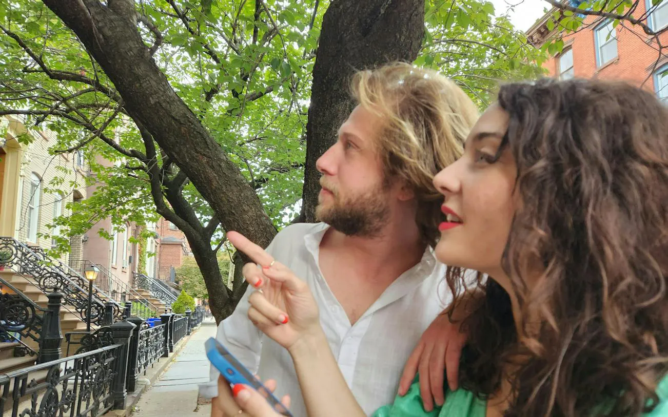 Couple exploring New York street with smartphone for Central Park self-guided game.