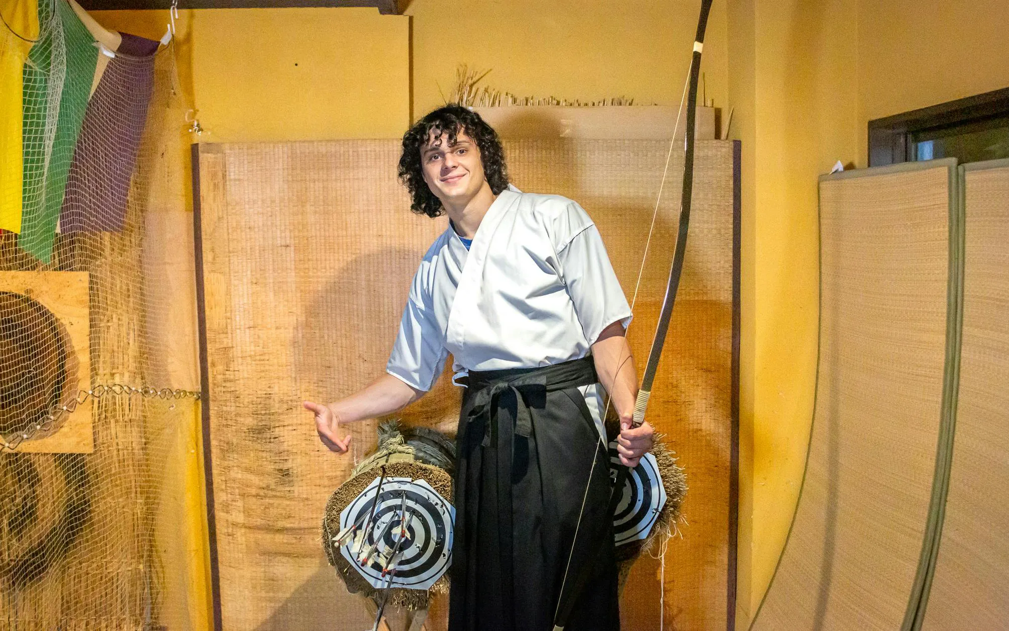 Person holding a bow in front of archery targets during a Japanese archery experience in Kyoto.