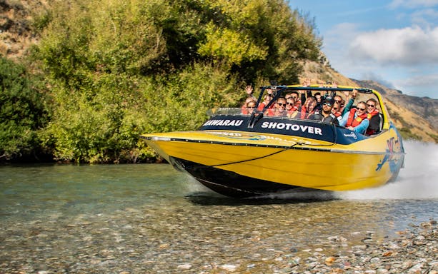 Jet boat on Kawarau and Shotover Rivers with mountains in the background.