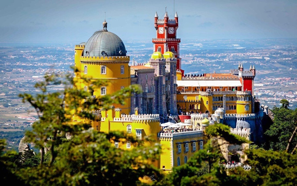 Pena Palace in Sintra, Portugal, with vibrant yellow and red towers.
