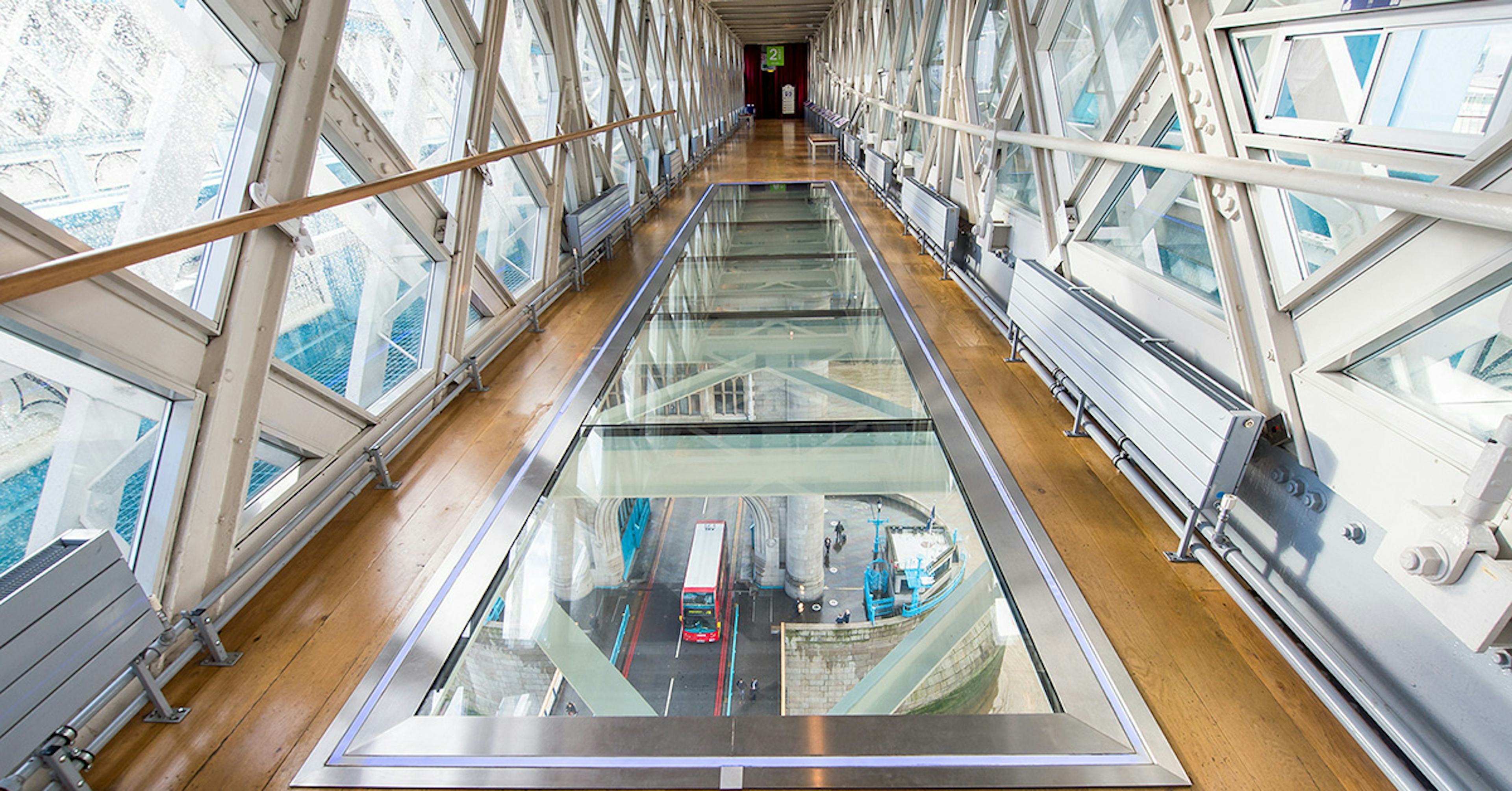 Glass walkway inside Tower Bridge with view of London street below.