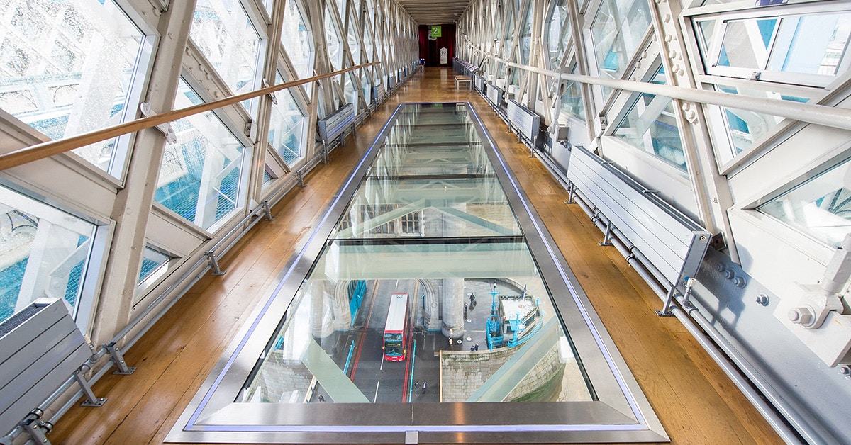 Glass walkway inside Tower Bridge with view of London street below.