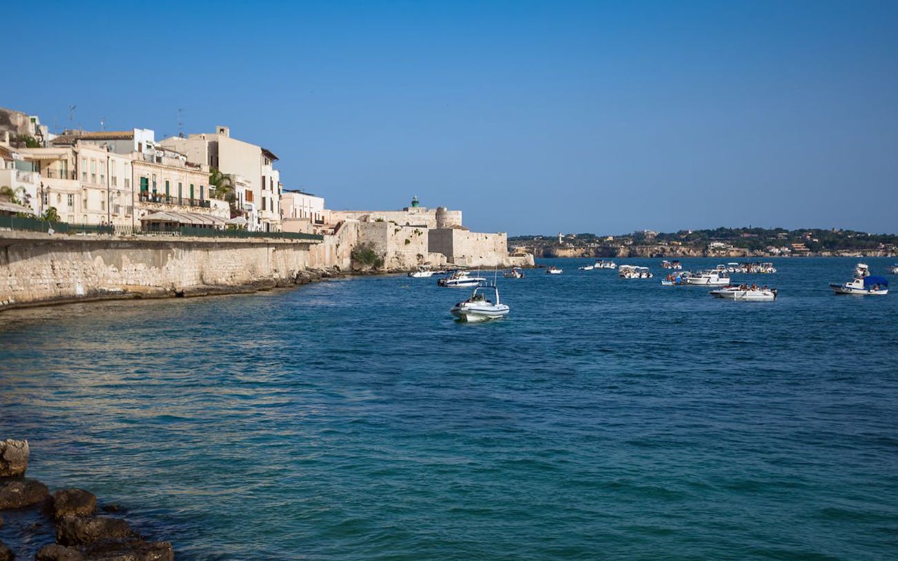 Boats on the water near historic buildings in Ortigia, Siracusa, Italy.