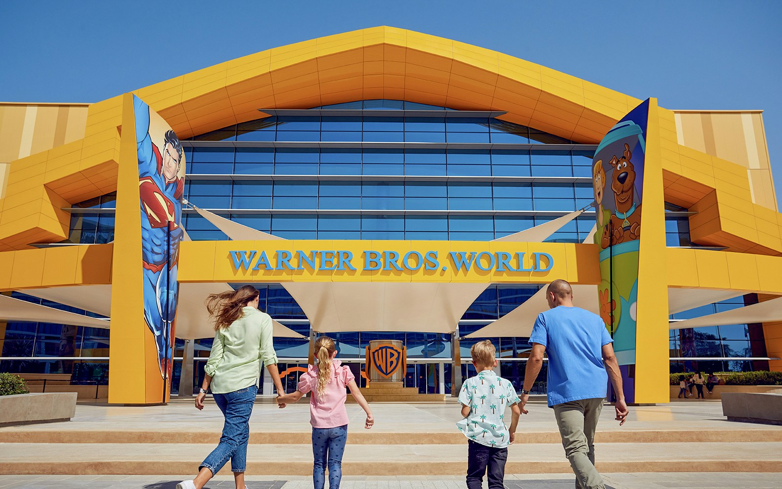 Family entering Warner Bros World Yas Island entrance with character murals.