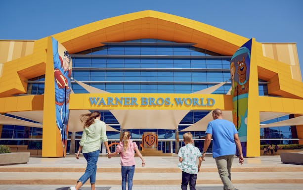 Family entering Warner Bros World Yas Island entrance with character murals.