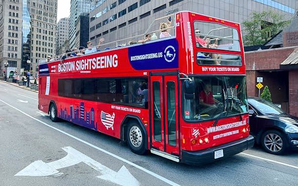 Red double-decker bus for Boston sightseeing tour on city street.