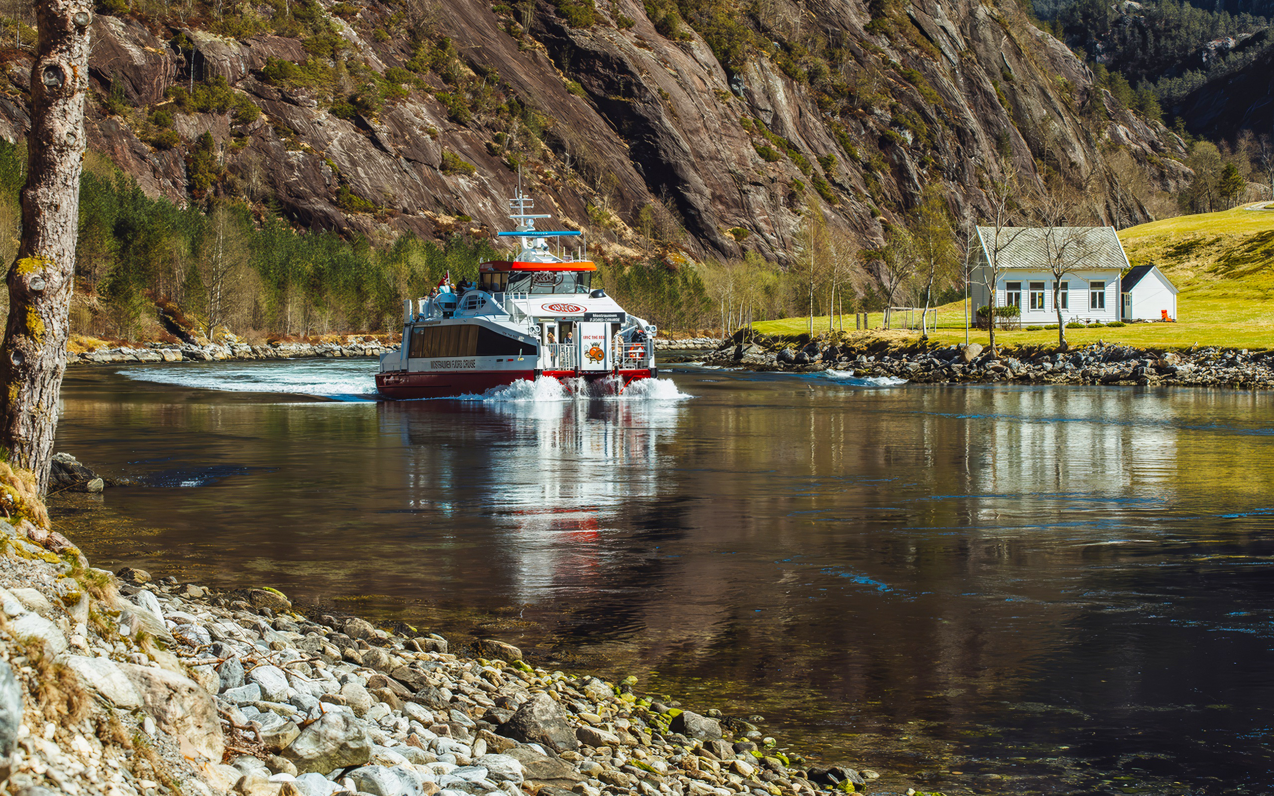 Cruise boat on Mostraumen Fjord near Bergen with scenic mountain backdrop.