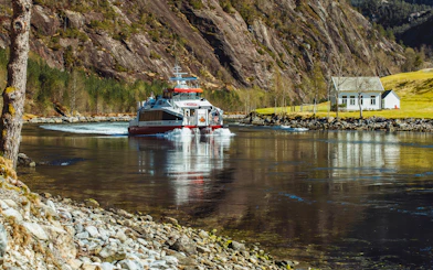 Cruise boat on Mostraumen Fjord near Bergen with scenic mountain backdrop.