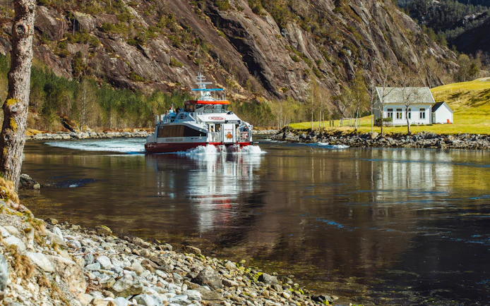 Cruise boat on Mostraumen Fjord near Bergen with scenic mountain backdrop.
