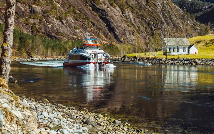 Cruise boat on Mostraumen Fjord near Bergen with scenic mountain backdrop.