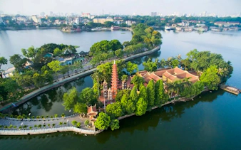 Tran Quoc Pagoda on West Lake, Hanoi, surrounded by lush greenery and water.