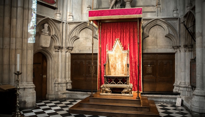 British Coronation Chair from the 1300s displayed in a historic exhibition setting.