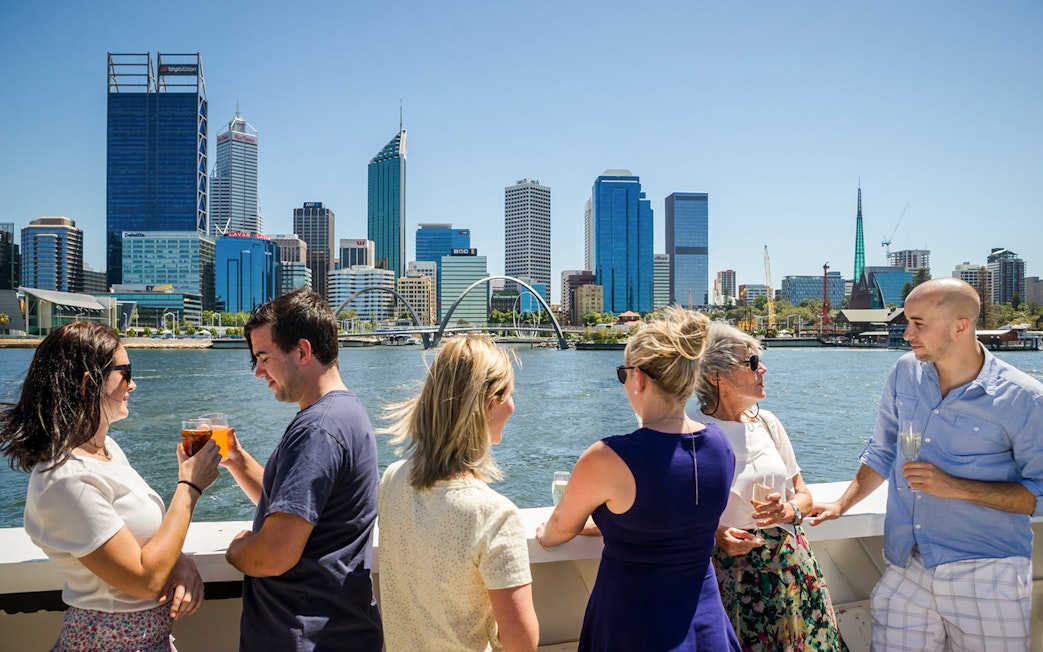 Cruise guests enjoying drinks with Perth skyline in the background.