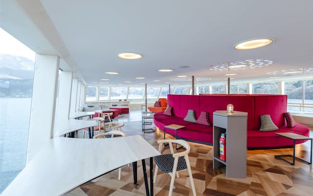 Interior seating area of Hakone Sightseeing Cruise with large windows and modern decor.