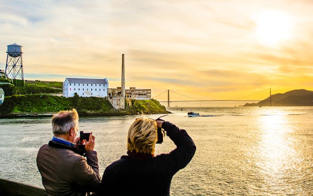 Guests photographing sunset near Alcatraz Island during California Sunset cruise.