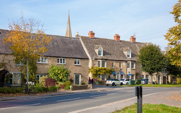 Stone cottages and a church spire in Bampton, London.