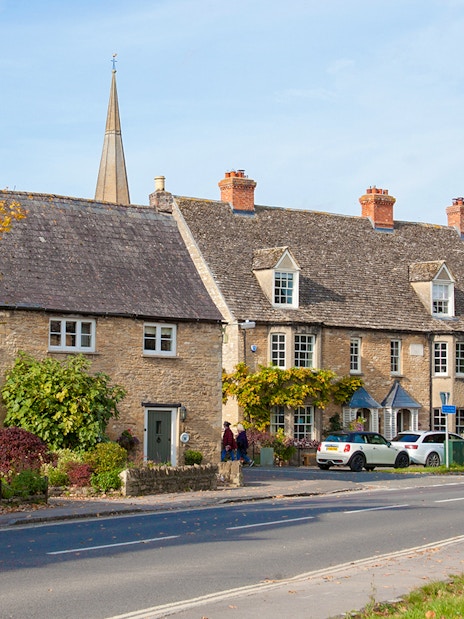 Stone cottages and a church spire in Bampton, London.