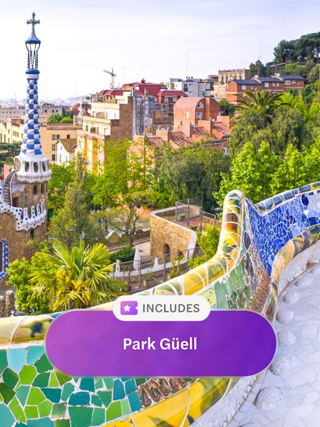 Park Güell's colorful mosaic terrace overlooking Barcelona cityscape.