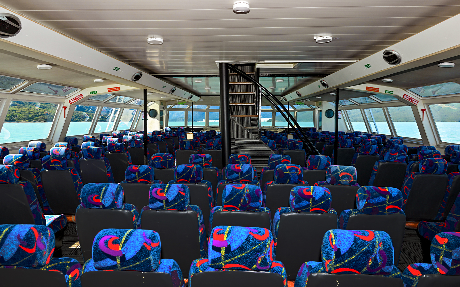 Interior seating of Perito Moreno Cruise with colorful patterned seats and large windows.