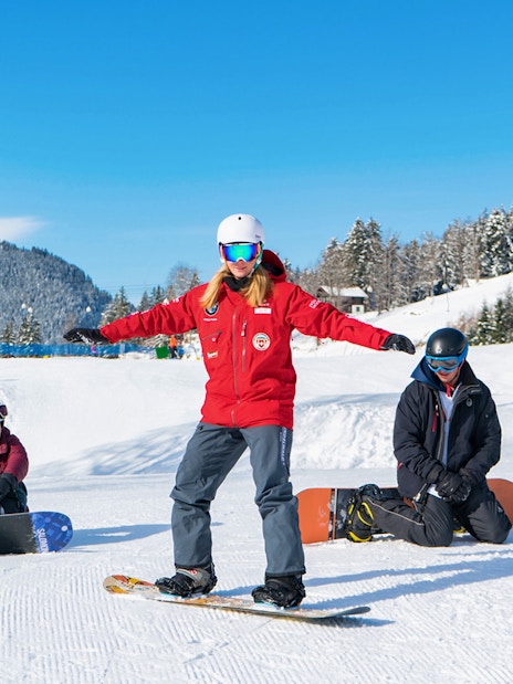 Beginner snowboarders learning on snowy slopes in Grindelwald with scenic mountain backdrop.